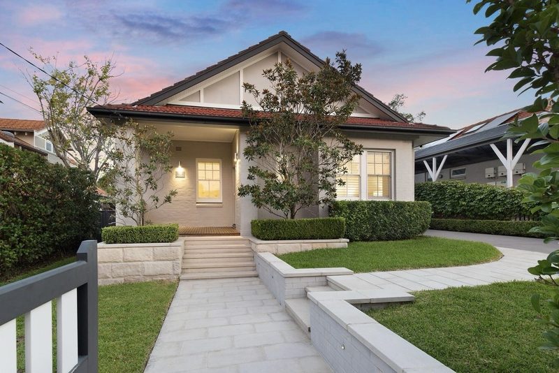 Restored bungalow at twilight with warm interior lighting, seen from the street, Roseville