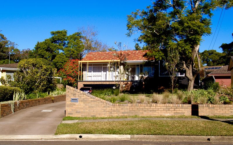 The house set high on its block above a curved brick retaining wall