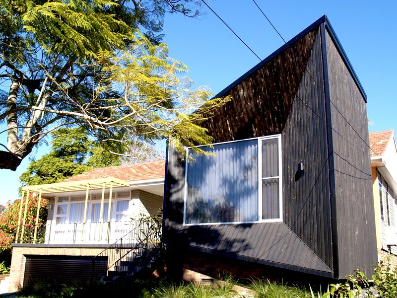 The 'barnacle': a blackened timber form with a large picture window, built to the proportions of the original house